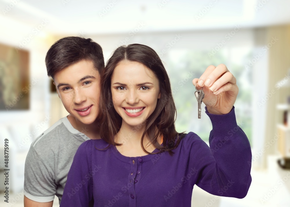 Fototapeta premium Happy millennial couple showing keys, smiling, hugging. Husband and wife, new homeowners, real estate property purchase, renting apartment.