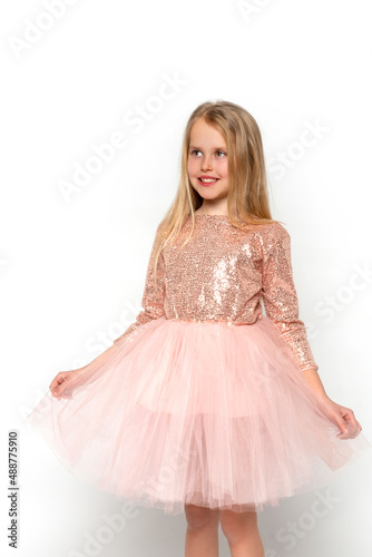 Studio shot of attractive little girl wearing pink ball gown and crown posing against white background in studio
