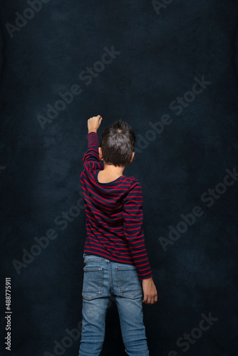 Young boy looks at the night sky and shows with his hand up in space