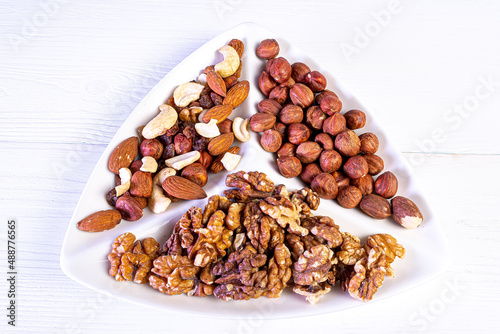 Various nuts close-up on a white plate on a white wooden table.