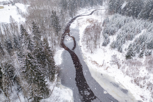 Forest river at blizzard in winter photo