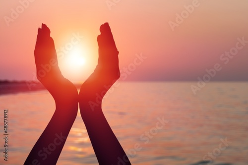 Summer sun concept with silhouette of young woman's hands relaxing, happy meditating
