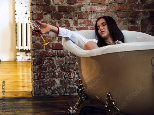 Girl in a loft bath with a glass of wine