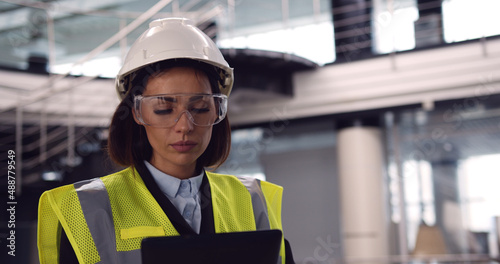 Close up of female architect standing inside empty office center holding a tablet checking building plan. Beautiful woman senior engineer controlling costruction process.