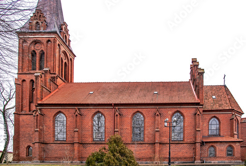 General view and close-up of architectural details of the Catholic church of Saint Bruno built in the neo-Gothic style in the city of Bartoszyce in warmi in Poland, built in the years 1882-83. photo