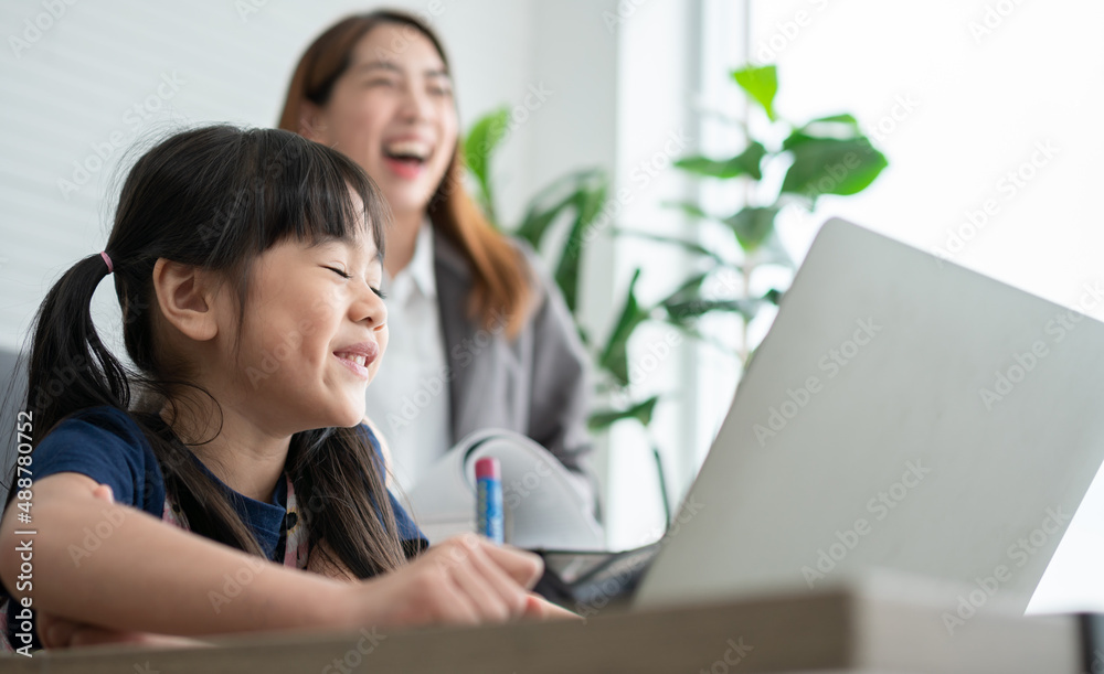Asian mother with her two grandchildren having fun and playing education games online with a digital computer laptop at home in the living room. Concept of online education and caring from parents.