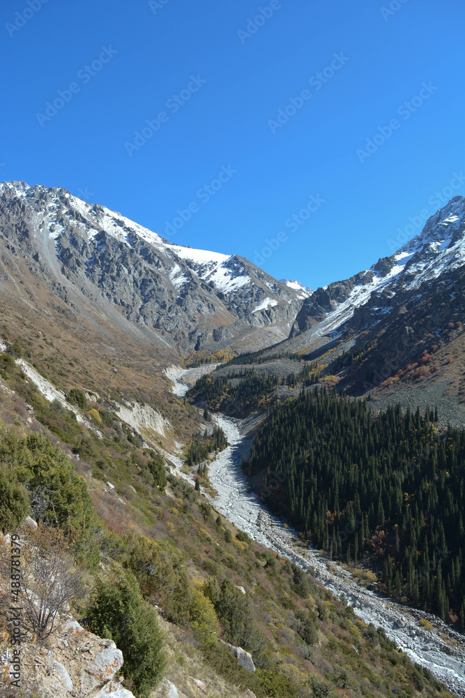 landscape in autumn mountain peaks with blu sky with snow with stones in dry river  in central asia kyrgyzstan
