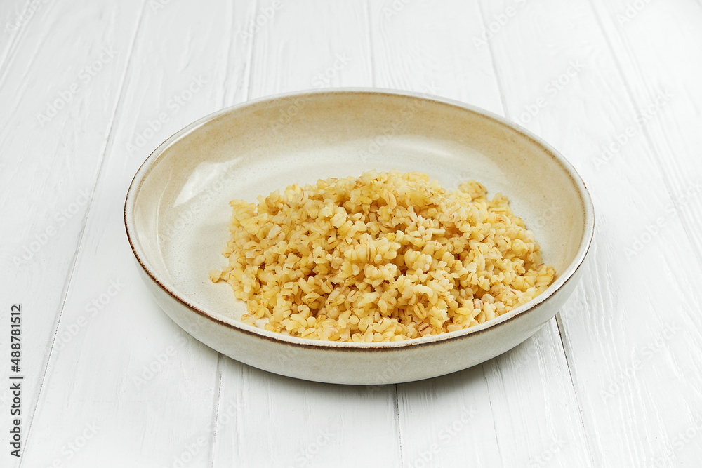 Dietary bulgur in a plate on a white wooden background Dietary bulgur in a plate on a white wooden background