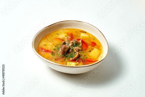 Chicken broth with meat, potatoes and bell peppers on white background