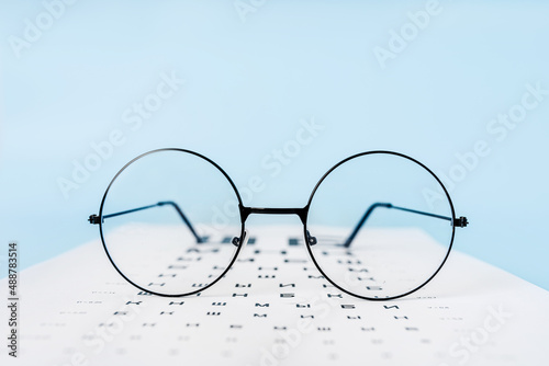 A table for checking vision in Russian, glasses and lenses on a light blue background. a concept for an ophthalmology clinic or the sale of optics