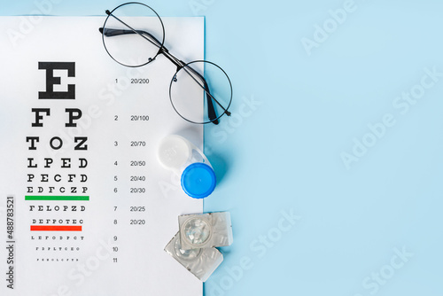 Fotografi A table for checking vision in Russian, glasses and lenses on a light blue background