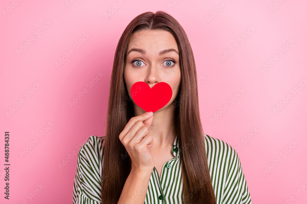 Photo of cute young brunette lady hold heart wear striped shirt isolated on pink color background