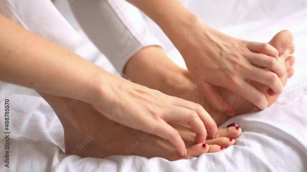 Side view of female hands scratch legs sitting on white bed at home. Itchy skin, fungus, fungal bacterial infection, allergic reaction, eczema, dermatitis of the foot. Health and skincare concept. Side view of female hands scratch legs sitting on white bed at home. Itchy skin, fungus, fungal bacterial infection, allergic reaction, eczema, dermatitis of the foot. Health and skincare concept.