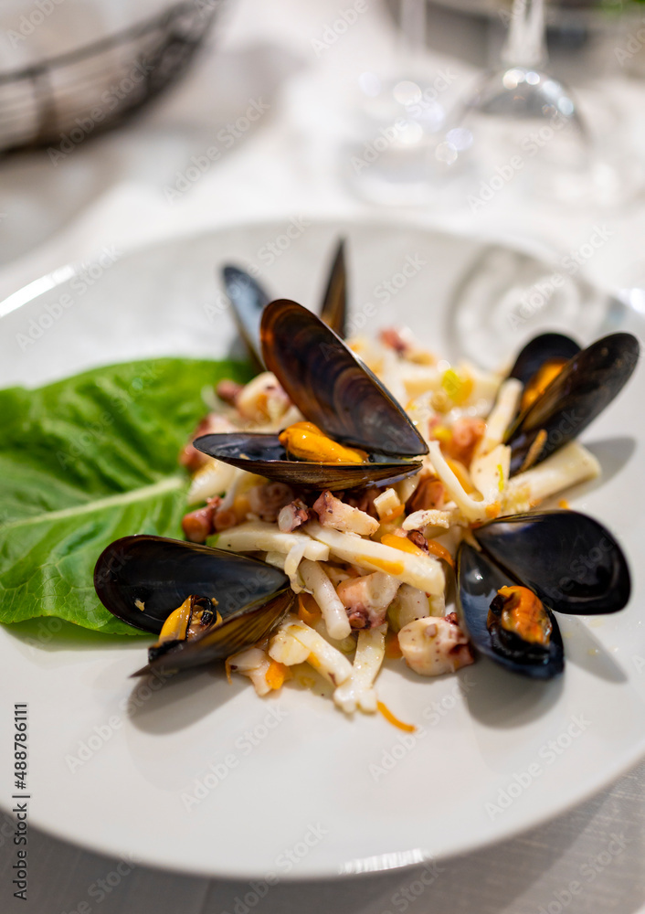 Tasty seafood salad with boiled octopus, potatoes, olive oil and mussels served in Italian restaurant