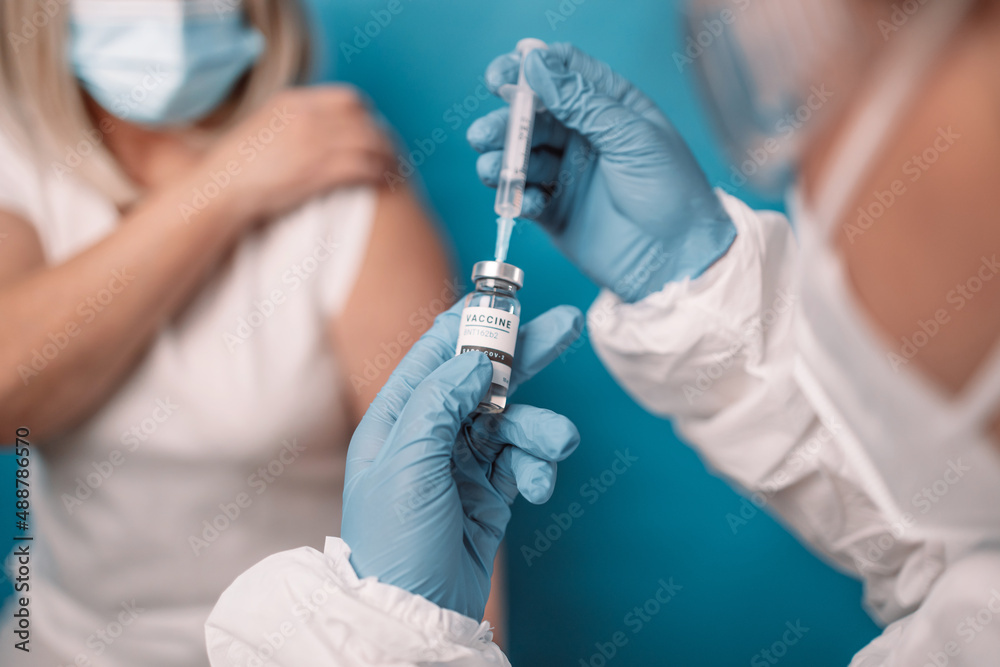 Close up of doctor or nurse hands taking covid vaccination booster shot or 3rd dose from syringe. - obrazy, fototapety, plakaty 