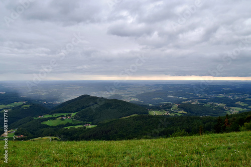 Grüne Hügellandschaft mit Regenschauer am Horizont (Oststeiermark, Österreich)