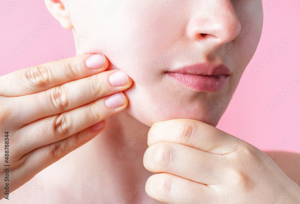 Female hands do self-massage of the face close-up on pink background. Female hands do self-massage of the face close-up on pink background.