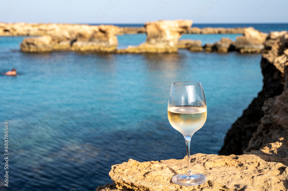 Glass of cold white dry white wine served on rocks in blue sea bay near Protaras touristic town on Cyprus Glass of cold white dry white wine served on rocks in blue sea bay near Protaras touristic town on Cyprus