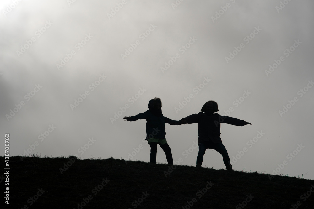 Father and daughter stand together on a hill and hang against the current Father and daughter stand together on a hill and hang against the current