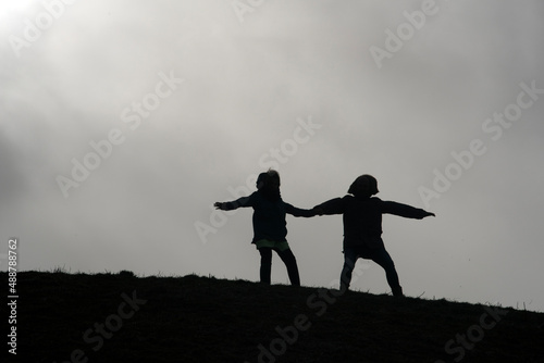 Father and daughter stand together on a hill and hang against the current