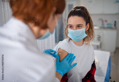 Young woman getting covid-19 vaccince from doctor in clinic. photo