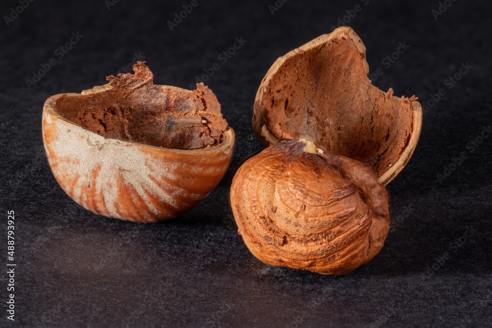 shelled hazelnuts and cracked shells from hazelnuts on a black background shelled hazelnuts and cracked shells from hazelnuts on a black background
