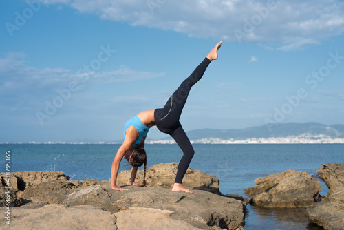 Woman doing yoga exercises on the beach in summer