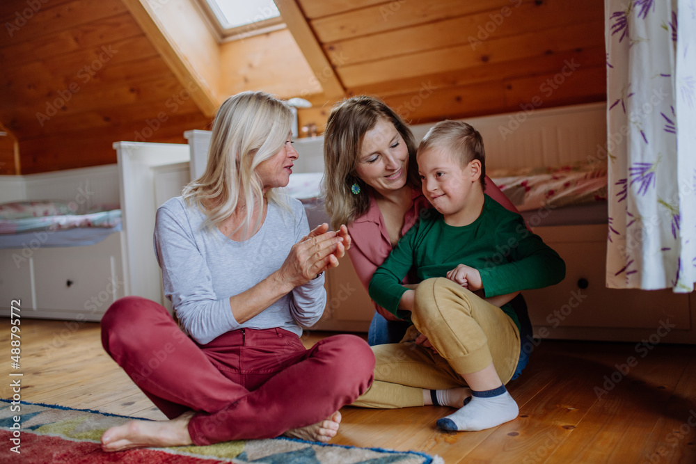 Boy with Down syndrome with his mother and grandmother at home. Boy with Down syndrome with his mother and grandmother at home.