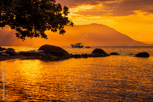 Fototapeta Naklejka Na Ścianę i Meble -  Warm sunset on beach and quiet ocean with boat in Florianopolis