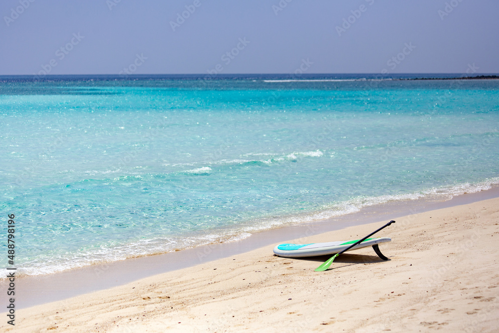 Sup Board on sandy beach in Maldives with writing 