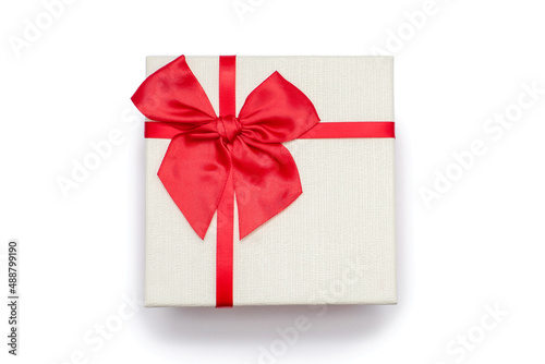 White gift box with a red ribbon and a bow on a white background. Gift for birthday or traditional holiday. Gift box close up