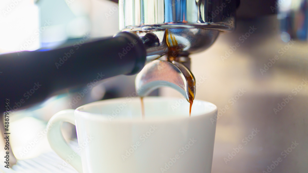 espresso coffee is pouring from the coffee machine into a white cup espresso coffee is pouring from the coffee machine into a white cup