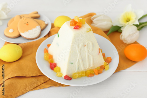 Delicious curd Easter cake with candied fruits and eggs on light wooden background