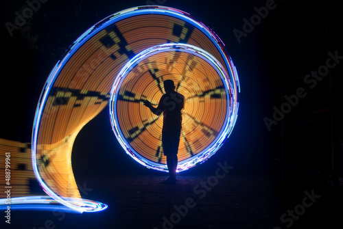 One person standing alone against beautiful color circle LED light painting as the backdrop 