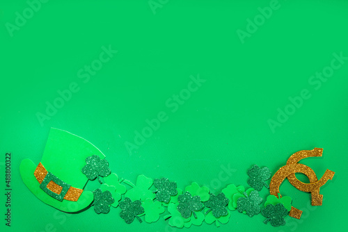 St Patrick flatlay background with shamrock clover leaves, leprechaun hat decor, golden coins and chocolates in form of symbol of st. patrick day