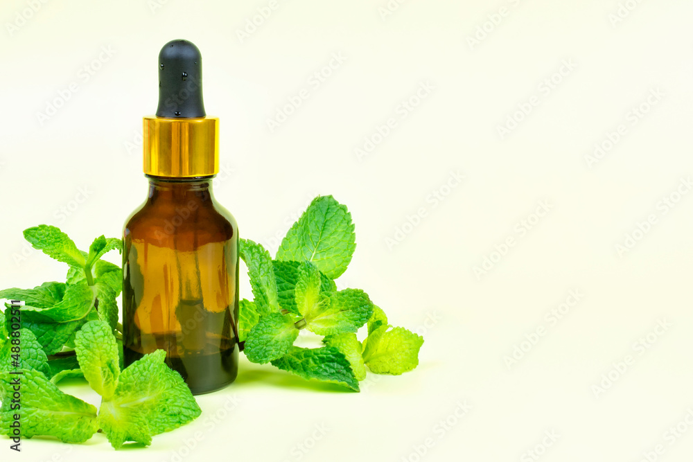 Essential oil of fragrant mint (peppermint) in a brown bottle with a pipette on a bright yellow background. Aromatherapy, spa, skin care. Space for text. Essential oil of fragrant mint (peppermint) in a brown bottle with a pipette on a bright yellow background. Aromatherapy, spa, skin care. Space for text.