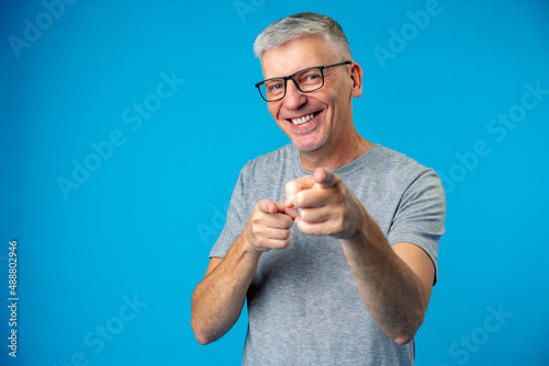 Handsome middle age senior man pointing at you over blue background