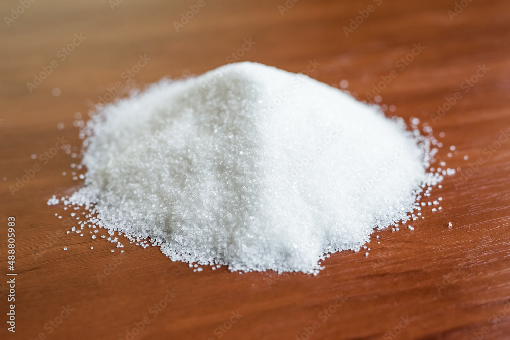 granulated sugar on a wooden background.