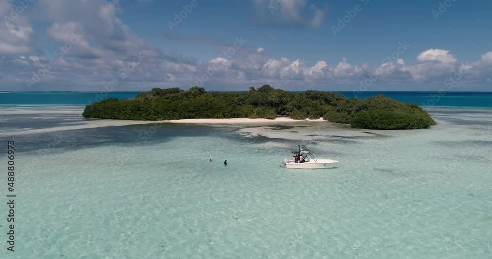 Aerial view move away on Bequeve tropical island with two children snorkeling near the boat Aerial view move away on Bequeve tropical island with two children snorkeling near the boat