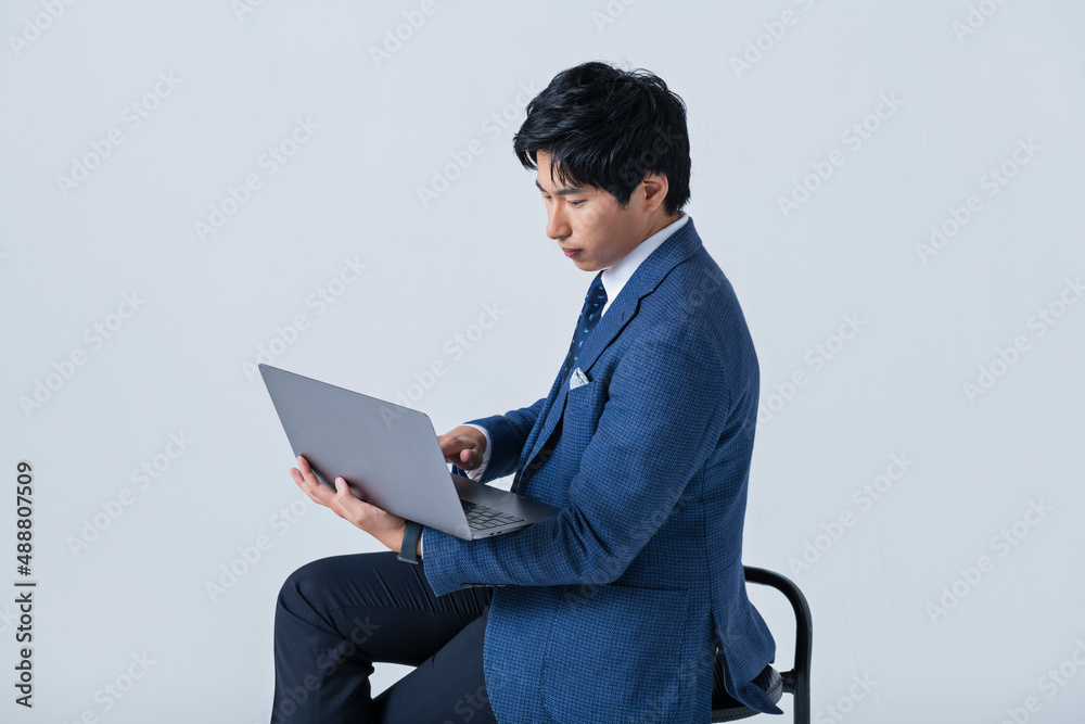 ノートパソコンを操作する20代ビジネスマン