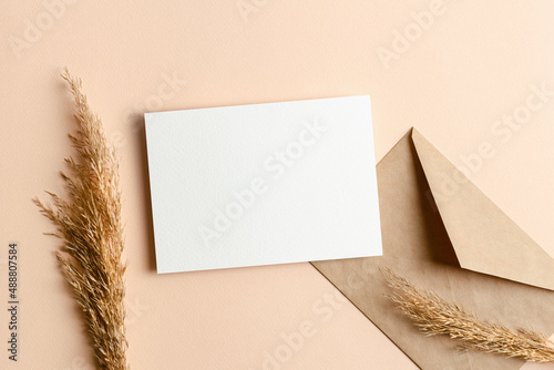 Wedding invitation card mockup with envelope and dry plant decorations on beige background