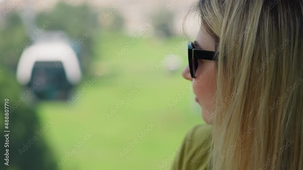 Thoughtful blonde woman tourist with sunglasses drives cabin of modern cable way enjoying landscape at mountain resort closeup slow motion Thoughtful blonde woman tourist with sunglasses drives cabin of modern cable way enjoying landscape at mountain resort closeup slow motion