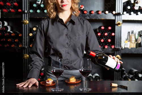 Unrecognizable woman pouring wine at counter with foie gras