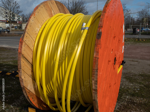 Wooden roller with yellow fiber optic cables for laying data cables at the construction site.