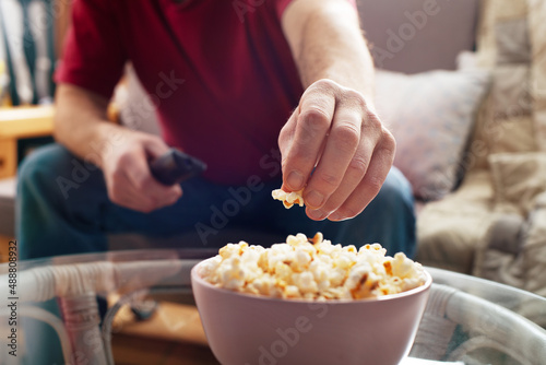 Obraz na płótnie Caucasian man sitting on sofa with popcorn and tv remote w salonie