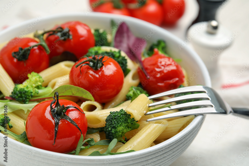 Bowl of delicious pasta with tomatoes, arugula and broccoli, closeup