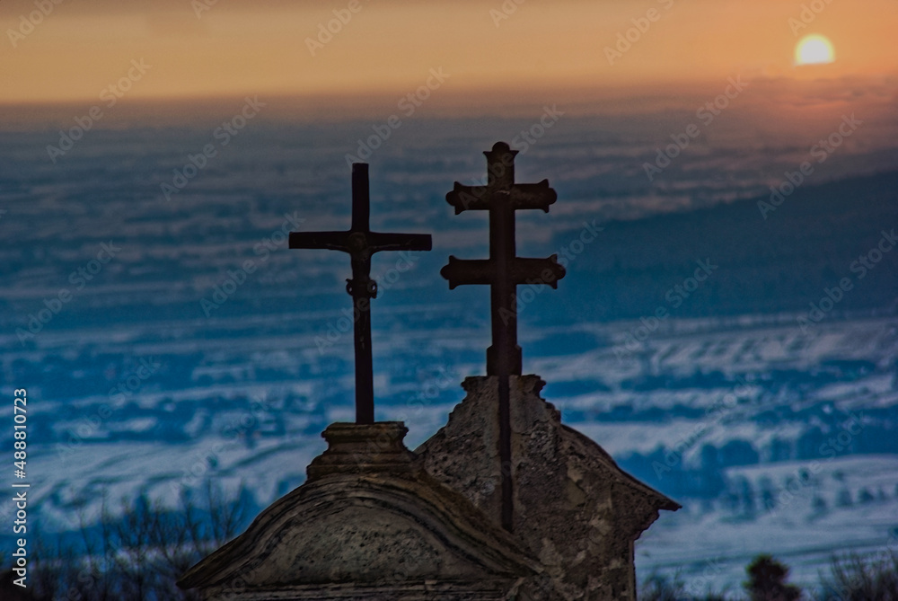 Klasztor Świętego Krzyża na Łyścu ( Łysej Górze) w Górach Świętokrzyskich w paśmie Łysogóry , krzyże nad bramą na tle śnieżnego krajobrazu podświetlonego wschodzącym słońcem .