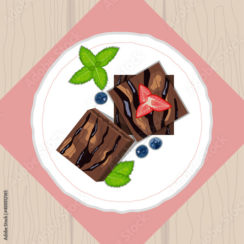 Brownies cake pieces with strawberries, blueberries and mint on ceramic plate top view
