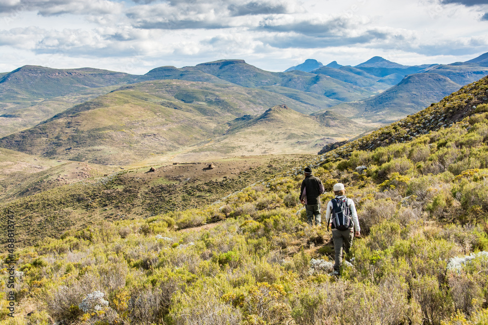 Travel to Lesotho. 2 hikers in the mountains with the shepherds' huts in the distance