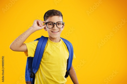 Happy school boy wearing glasses, holding backpack going to school, enjoying studying,